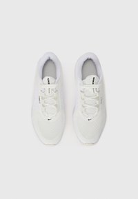 Zapatillas deportivas blancas de malla con puntas redondas, cordones planos y un logotipo negro de Nike en el lateral y la lengüeta. Tejido texturizado y suelas de goma.
