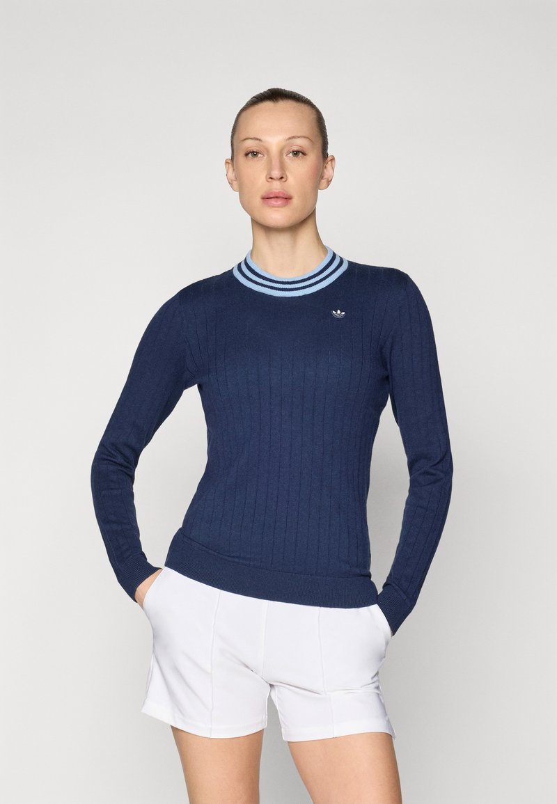 Marineblauwe geribde trui met een ronde halslijn en een lichtblauwe gestreepte kraag; heeft een klein Adidas-logo op de borst.