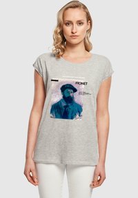 Grå t-shirt med korte ærmer og løs pasform, præget af et grafisk motiv af Claude Monets portræt i blå nuancer med tekstakcenter.
