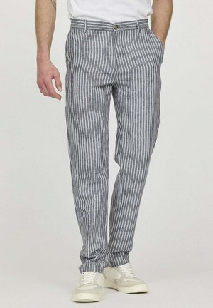 Pantalons rayés gris en tissu léger, avec une coupe ajustée, des poches avant et une fermeture à bouton. Associés à des baskets blanches.