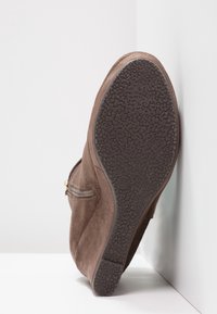 Stivale alla caviglia in suede marrone con suola in gomma testurizzata, zip laterale e punta arrotondata. Taglia segnata come 37 sulla suola.