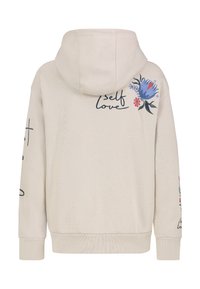 Beiger Kapuzenpullover mit Kordelzugkapuze, blau-rotem, gesticktem Blumendesign und dem Schriftzug "self love" auf Rückseite und Ärmeln.