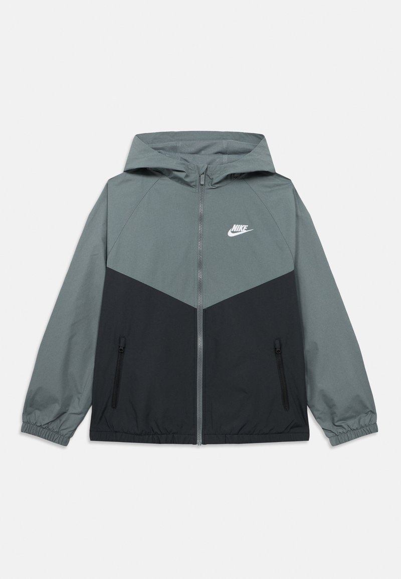 Γκρι και μαύρο αδιάβροχο μπουφάν με κουκούλα, με φερμουάρ σε πλαϊνές τσέπες και λευκό λογότυπο στο στήθος, κατασκευασμένο από ελαφρύ υλικό.