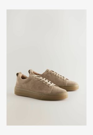 Beige ruskindssneakers med flade snørebånd, lavt snit og gummisål. Har en sømløs tåhætte og syningsdetaljer.