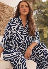 Marineblauw en wit gestreepte shirt- en broekset van lichtgewicht stof, met een losse pasvorm, knopen en twee voorzakken.