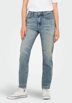 Jean taille haute bleu clair avec une coupe droite. Le matériau en denim présente un léger délavage et des détails de couture subtils. Porté avec des baskets blanches.