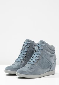 Suede high-top sneakers in light blue with perforated details, flat laces, padded collar, and a concealed wedge heel. Smooth rubber sole.