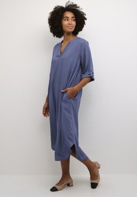 Robe légère de longueur genou en bleu ardoise avec un décolleté en V, des manches trois-quarts, des poches latérales et une coupe décontractée.