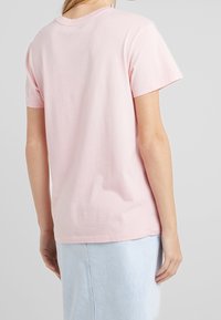 Růžové bavlněné tričko s kulatým výstřihem a krátkými rukávy, s volným střihem. Hladká textura a jednoduchý design.