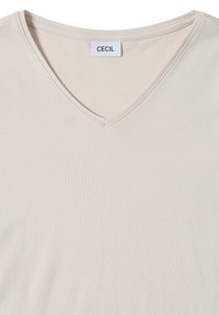 Vaalea beige V-kaula-aukko t-paita, joka on valmistettu sileästä ja pehmeästä kankaasta. Siinä on hienovarainen kiilto ja yksinkertainen muotoilu. Brändilogo näkyvissä kaula-aukossa.