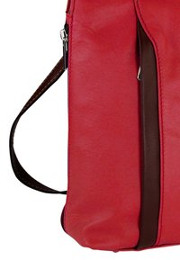 Rode leren tas met een zachte textuur, voorzien van een bruine leren accent en verstelbare schouderriem, bevestigd met zilverkleurige beslag.