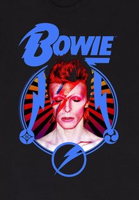 T-shirt nera con una stampa vivace raffigurante una figura dai capelli rossi con un trucco a forma di fulmine, incorniciata da cerchi e raggi dinamici in blu e rosso.