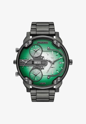 Montre Diesel avec cadran vert texturé, quatre sous-cadrans affichant plusieurs fuseaux horaires, boîtier et bracelet en métal argenté, et affichage de la date à 3 heures.