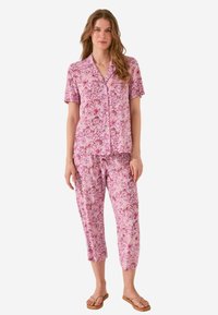 Twee-delige pyjama set in het roze met bloemmotieven, met een kort mouwtop en cropped broek. Gemaakt van zachte stof met een knoopsluiting.