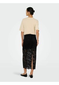 Beež värvi ülisuur t-särk, millele on lisatud must pitsist midi seelik lillemustritega ja küljeäärest lõhikuga, mida täiustavad mustad kingad.