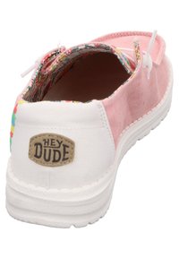 Scarpe slip-on in tessuto rosa con suola in gomma bianca, caratterizzate da una fodera a fantasia colorata e una patch con il logo "HEY DUDE" sul tallone.