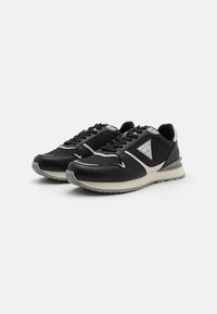 Zapatillas deportivas negras con parte superior de cuero sintético, detalles en plateado y logotipo en el costado. Suela acolchada con suela exterior de goma gris.