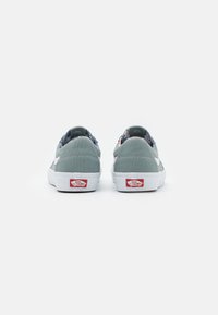 Gray canvas sneakers with white rubber soles, featuring a patterned inner lining, contrasting white and red accents, and classic low-top design.