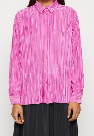 Camicia rosa a maniche lunghe con piastre verticali, abbottonatura frontale e colletto classico; presenta una texture liscia e lucida e maniche con polsini.
