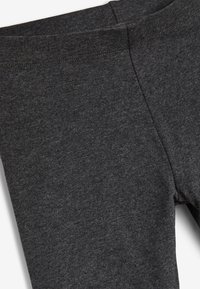 Leggings grises hechos de un tejido suave y elástico. Cuentan con una cintura elástica y una textura lisa, con costuras mínimas visibles.