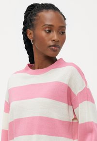 Maglione a righe in morbido tessuto a maglia. Righe orizzontali rosa e bianche, scollo rotondo, vestibilità comoda e polsini a coste.