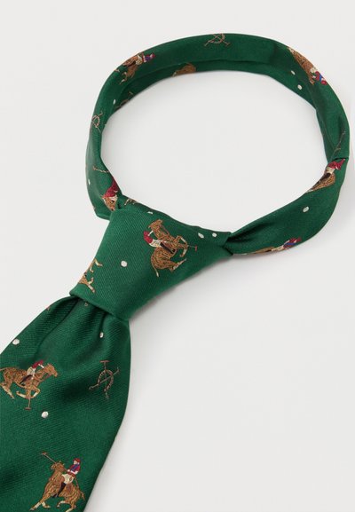 Zielony jedwabny krawat z wzorami polo – jeźdźca i pałki w kolorach czerwonym, brązowym i białym, związany w węzeł Windsor na białym tle.