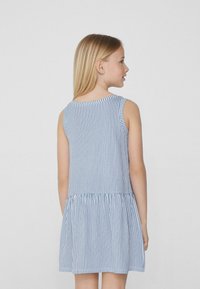 Robe sans manches présentant des rayures verticales bleues et blanches, un col rond et une jupe évasée froncée pour un effet superposé.