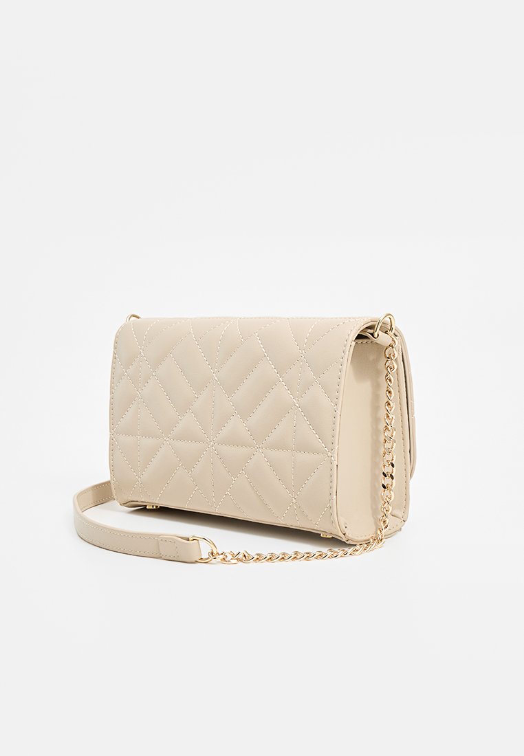 Bolso cruzado de cuero beige acolchado con correa de cadena en tono dorado. Presenta un acolchado geométrico y una forma rectangular. Diseño compacto y estructurado.