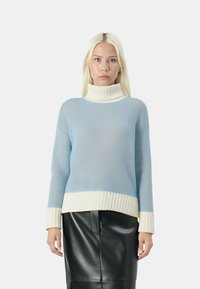 Maglione a collo alto lavorato a maglia di colore blu chiaro con polsini e orlo a coste bianchi, caratterizzato da un design testurizzato e spalle scese, abbinato a una gonna in pelle nera.