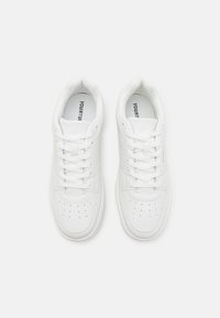 Hvide sneakers lavet af glat læder, med perforeringer på tåen, flade snørebånd og en polstret indersål med brandtekst indeni.