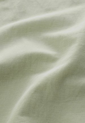 Heleroheline tekstuuriga kangas, kus on nähtav peen koeskeem ja pehmed voldid, mis loovad õrnu varje.