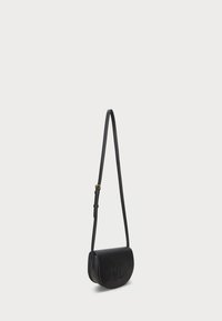 Black leather crossbody bag with a curved design, featuring an embossed logo, a long adjustable strap, and a smooth textured finish.
