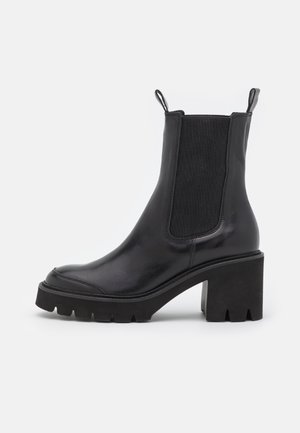 Schwarzer knöchelhoher Stiefel mit klobigem Absatz, elastischem Seiteneinsatz und Zuglaschen, ausgestattet mit einer groben Sohle für besseren Halt.