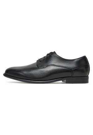 Zwarte leren nette schoen met een gladde afwerking, afgeronde neus, veterontwerp en lage hak. Voorzien van subtiele stikselaccenten.