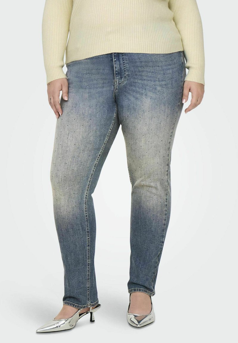Donkerblauwe denim jeans met een vervaagde afwerking, met een slim fit ontwerp en subtiele whiskering. Gecombineerd met glanzende zilveren hakken.