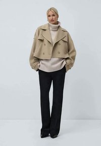 Beige cropped double-breasted jacket over a light knit turtleneck, paired with black wide-leg trousers. Smooth texture, simple design.