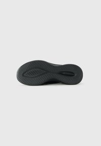 Black sneaker sole with textured grooves and a central wave-shaped groove pattern on a plain white background.