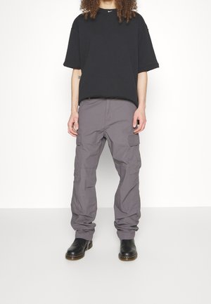 Czarna koszulka z krótkim rękawem z logo Nike, zestawiona z szarymi spodniami cargo z wieloma kieszeniami i luźnym krojem, noszona z czarnymi butami.