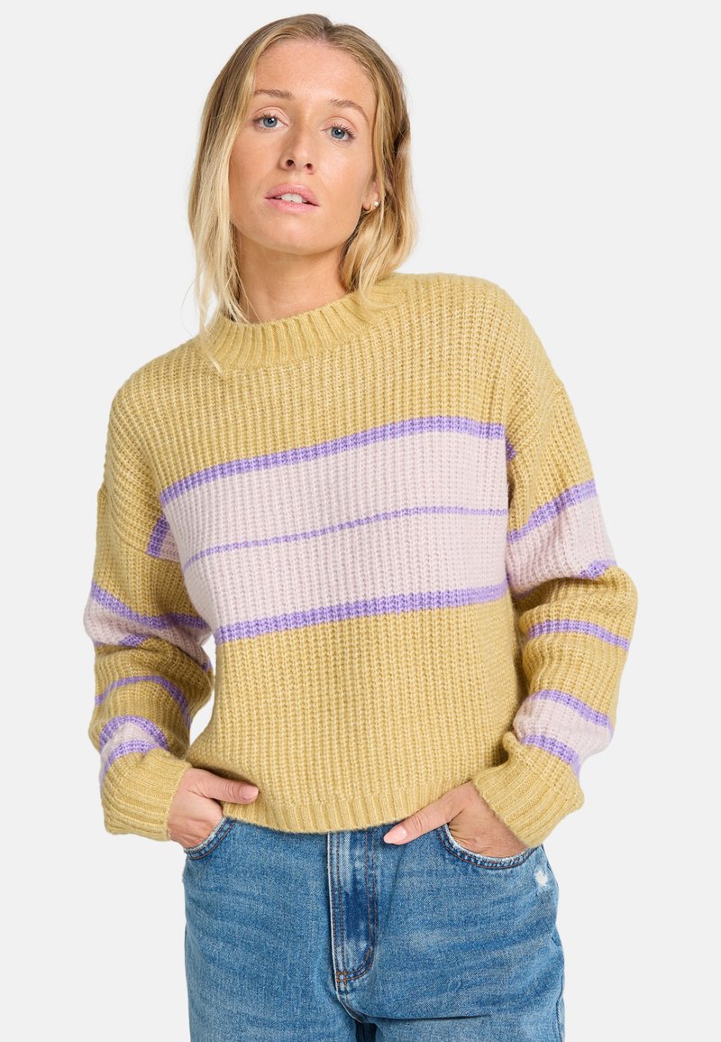 Maglione lavorato a maglia giallo con strisce orizzontali viola e rosa. Presenta un collo rotondo e polsini a costine, abbinato a jeans blu.