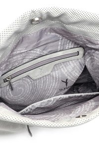 Intérieur gris d'un sac avec une poche zippée, tissu texturé et motif de texte imprimé. Le matériau extérieur présente des perforations blanches.