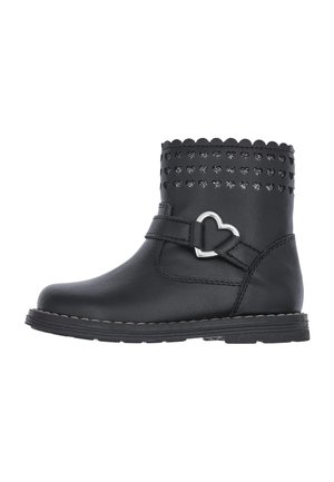 Botte cheville en simili cuir noir avec un haut en forme de vagues, une boucle en forme de cœur et un design clouté. Semelle texturée avec des coutures contrastées.