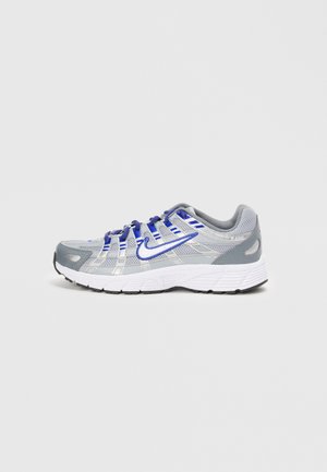 Chaussure de sport grise avec une tige en mesh, des accents argentés, des lacets bleus et une semelle blanche. Caractéristiques : un orteil arrondi et un marquage minimal.