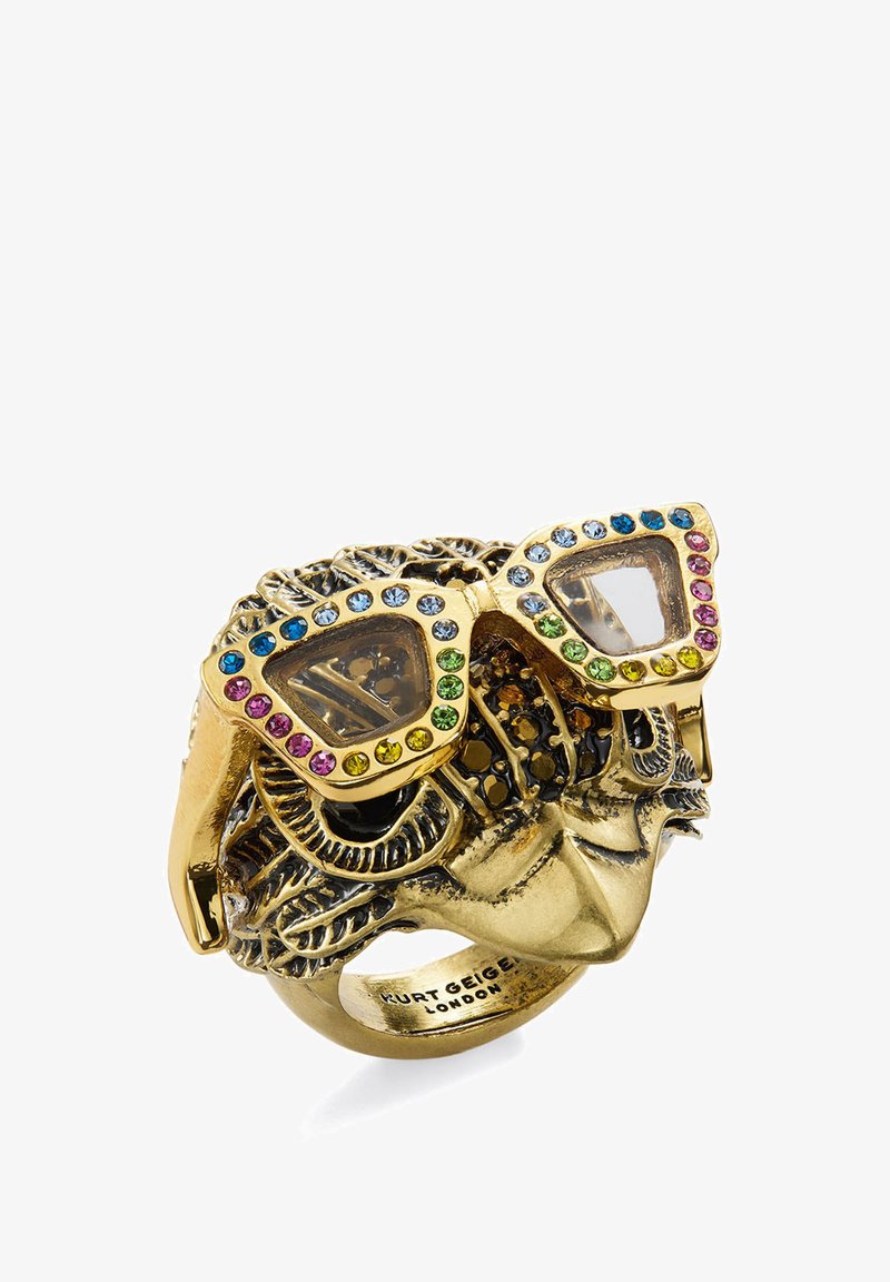 Goldfarbener Ring in Form eines kunstvoll gestalteten Gesichts mit farbenfroh mit Edelsteinen besetzten Cat-Eye-Brillen, innen mit "Kurt Geiger London" graviert.