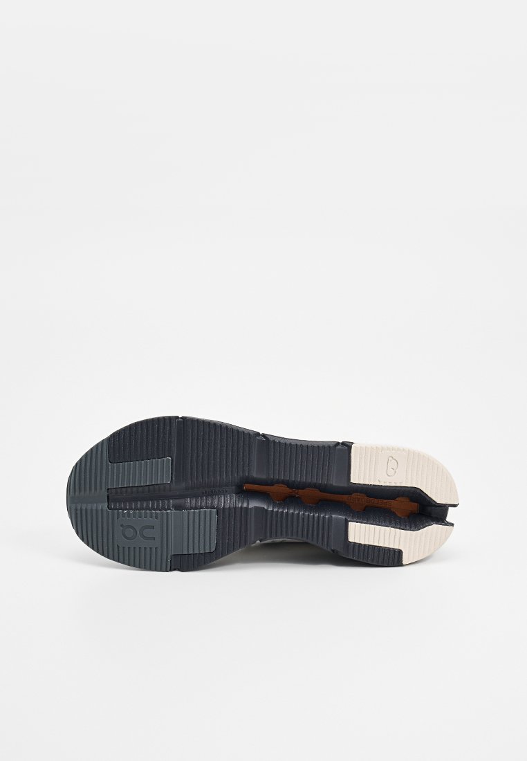 Schuhsohle mit schwarzen, weißen und grauen Profilbereichen, ausgestattet mit einem geteilten Zehendesign und sichtbaren Profilmustern für Traktion und Flexibilität.