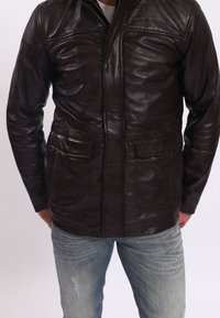 Braune Lederjacke mit einem Frontreißverschluss, zwei Brusttaschen und zwei unteren Klapptaschen; sie hat eine glatte Oberfläche und ein klassisches Design.