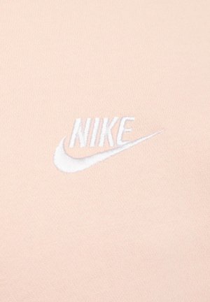 Pink cotton fabric features a white embroidered Nike logo with a swoosh design, centered for visibility. Smooth texture, minimalistic style.