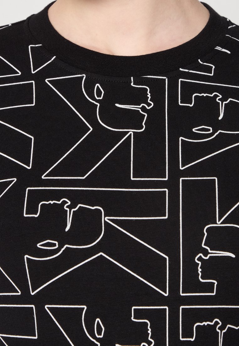 T-shirt in tessuto nero con un audace motivo geometrico bianco, caratterizzato da vari volti in profilo stilizzati e forme angolari.