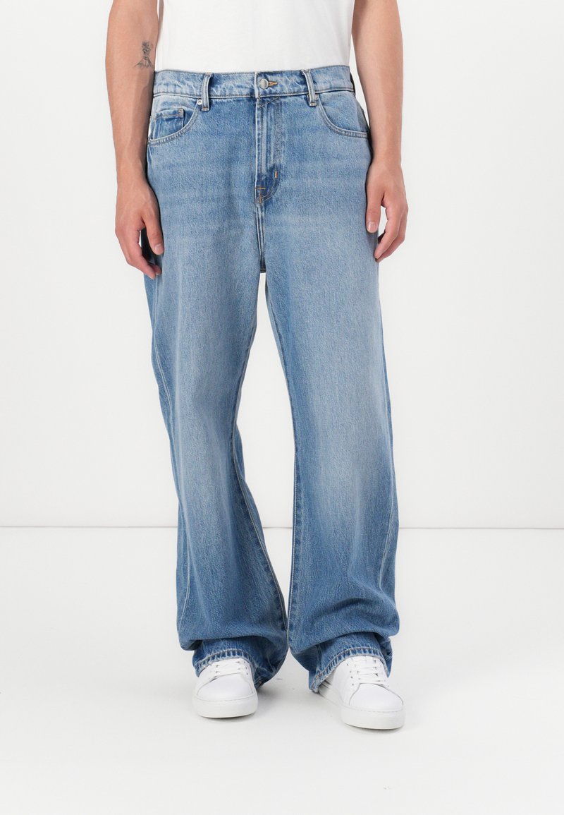 Jeans de mezclilla de color azul claro con un corte holgado, cinco bolsillos y cierre de botones. Presenta un ligero desvanecimiento y costuras en contraste.