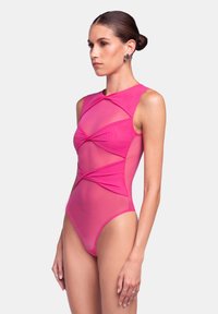 Costume intero rosa brillante con un design strutturato, caratterizzato da pannelli trasparenti e dettagli in tessuto torciti sul corpetto.