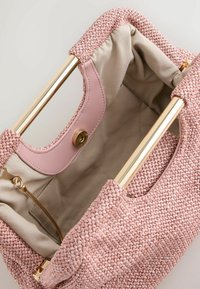 Ručne tkaná ružová kabelka so zlatým kovovým rámom, béžovým látkovým vnútrom, ružovým koženým magnetickým zapínaním a vnútorným vreckom na zips.